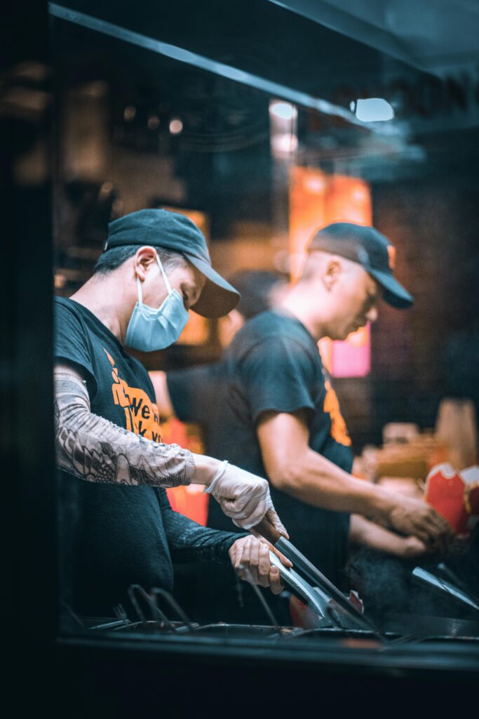 Two chefs working diligently in a fast food restaurant kitchen with focus and precision.